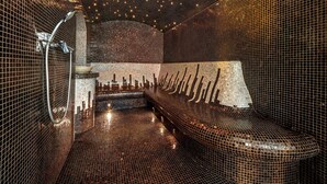 Una sauna moderna con azulejos, una banca y ducha empotrada en la pared.