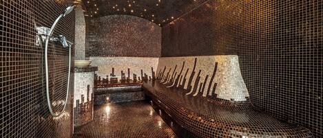 Una sauna moderna con azulejos, una banca y ducha empotrada en la pared.