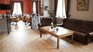 Un salon avec une table basse en bois, un canapé en cuir marron et un coin repas comprenant des tables et des chaises en bois.
