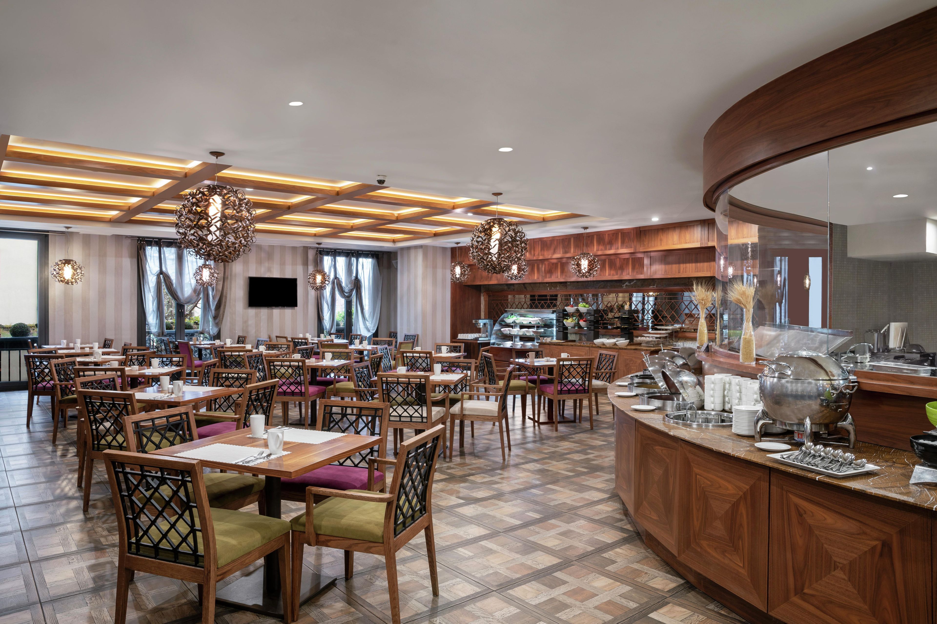 A restaurant with wooden furniture, a buffet area, and pendant lighting.