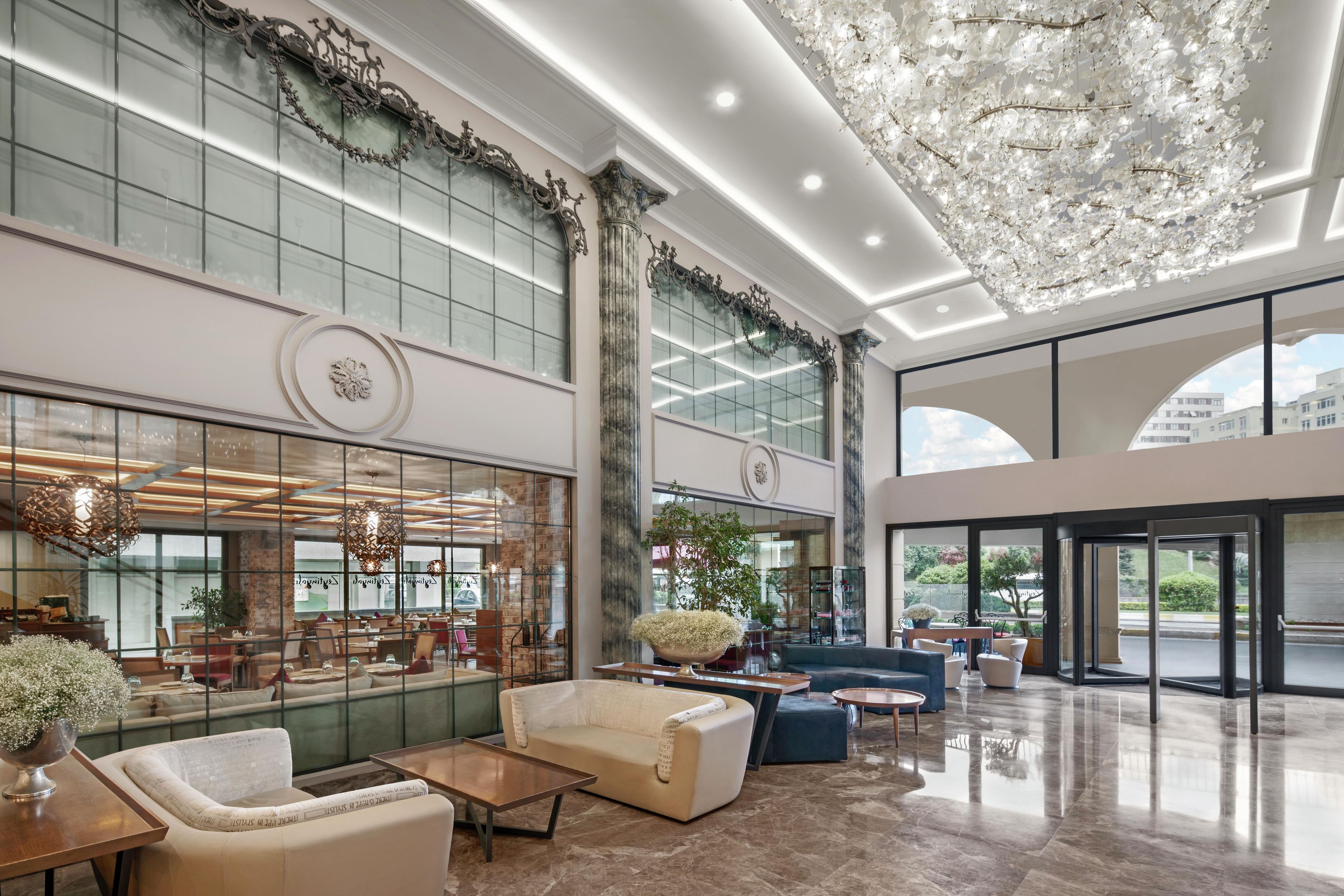 A spacious lobby with a high ceiling, large windows, and modern furnishings.