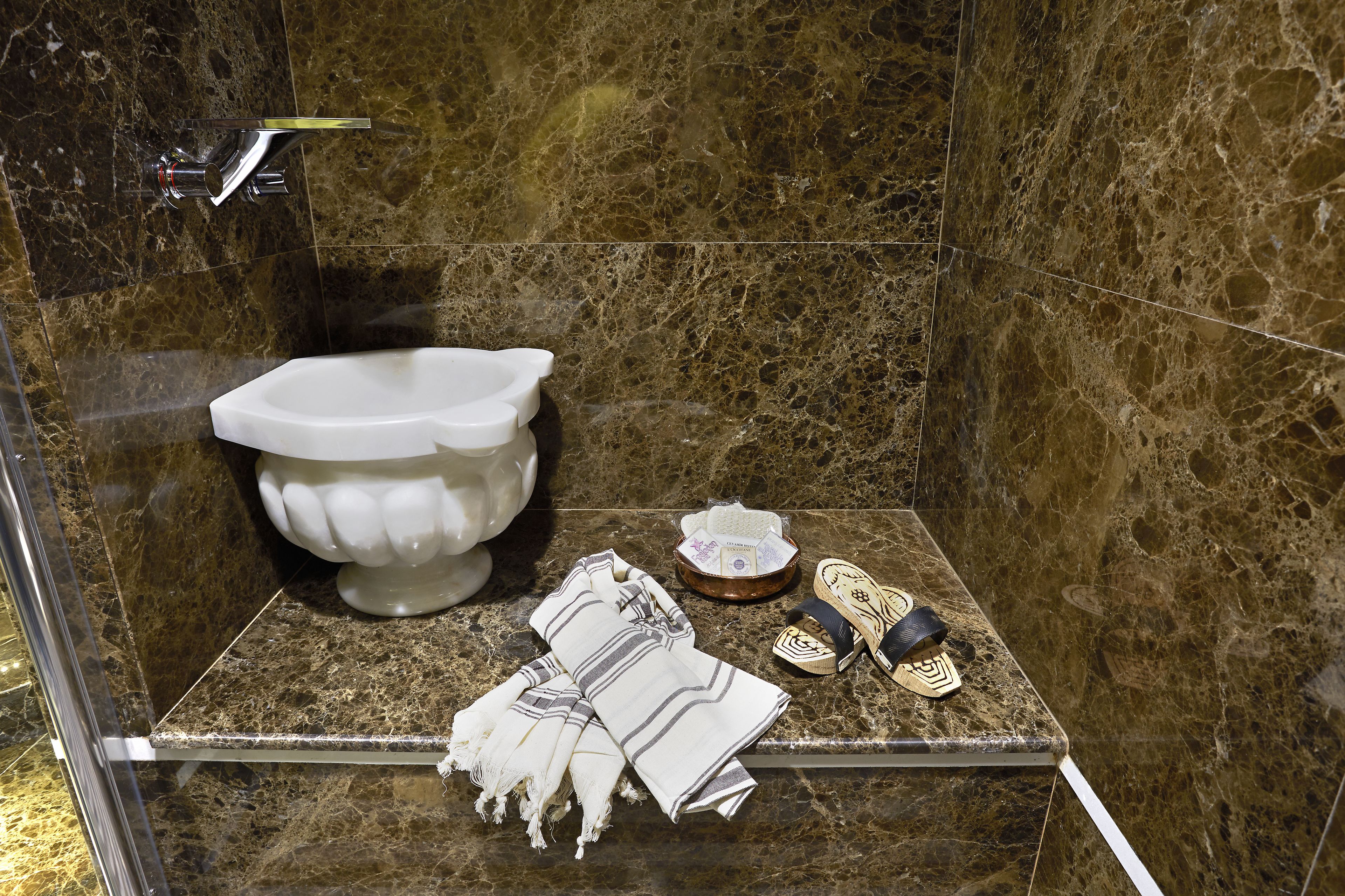 A bathroom with a marble sink, a toilet, and a shower area.