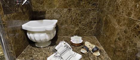 A bathroom with a marble sink, a toilet, and a shower area.