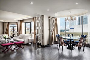 A modern hotel room with a dining area, a sofa, a coffee table, and a view of the cityscape. - DoubleTree By Hilton Istanbul Gayrettepe (Istanbul)