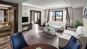A modern hotel room with a marble bathroom, a sofa, a dining table, and a large window with a city view. - DoubleTree By Hilton Istanbul Gayrettepe (Istanbul)