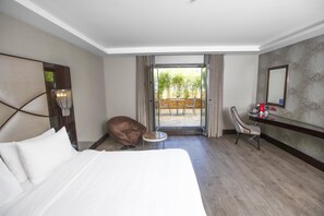 A hotel room with a bed, a chair, a small table, a desk with a mirror, and a view of the outdoors. - DoubleTree By Hilton Istanbul Gayrettepe (Istanbul)