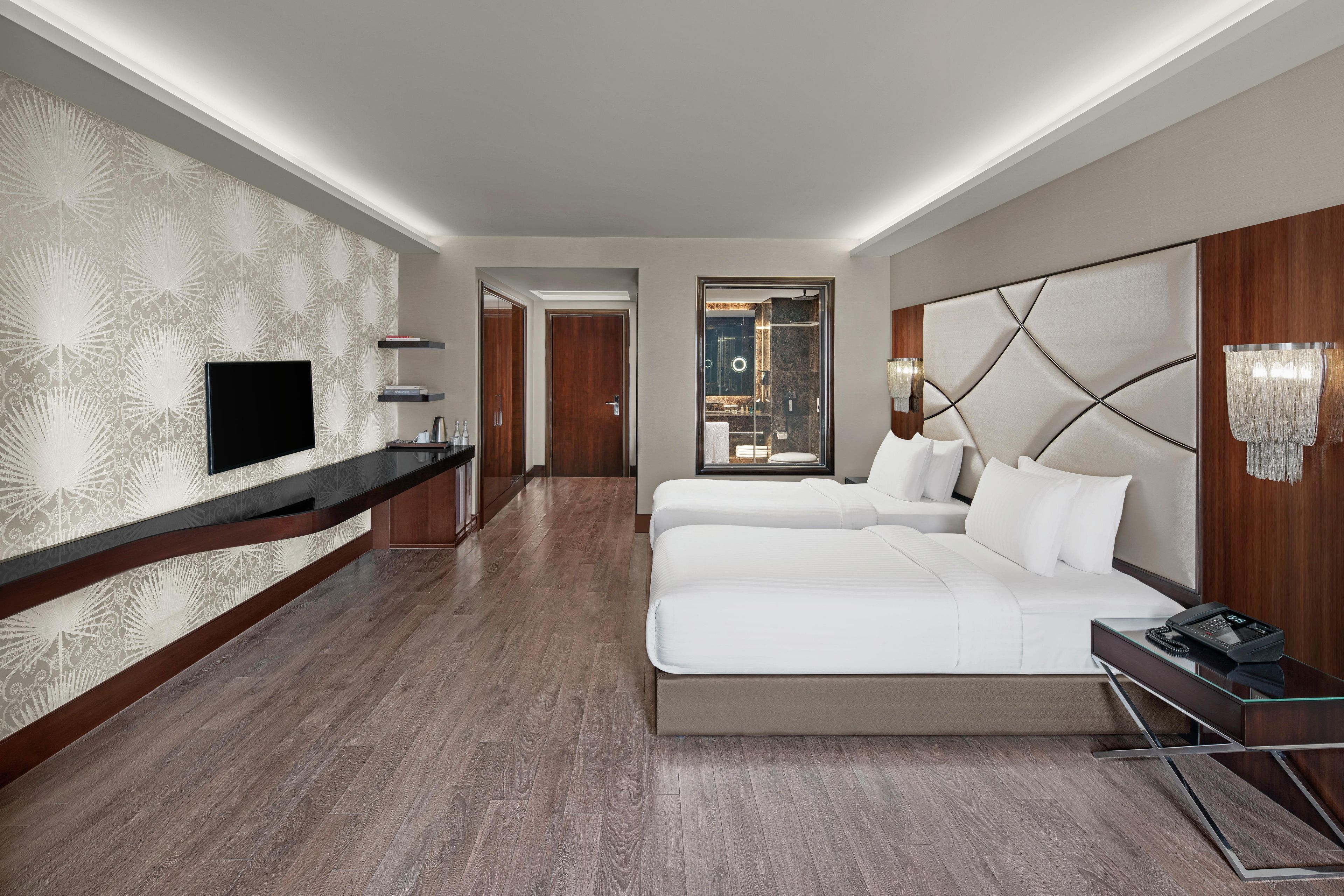 Ein Hotelzimmer mit einem großen Bett, einem Fernseher, einer Minibar und einem durch eine offene Tür einsehbaren Badezimmer.