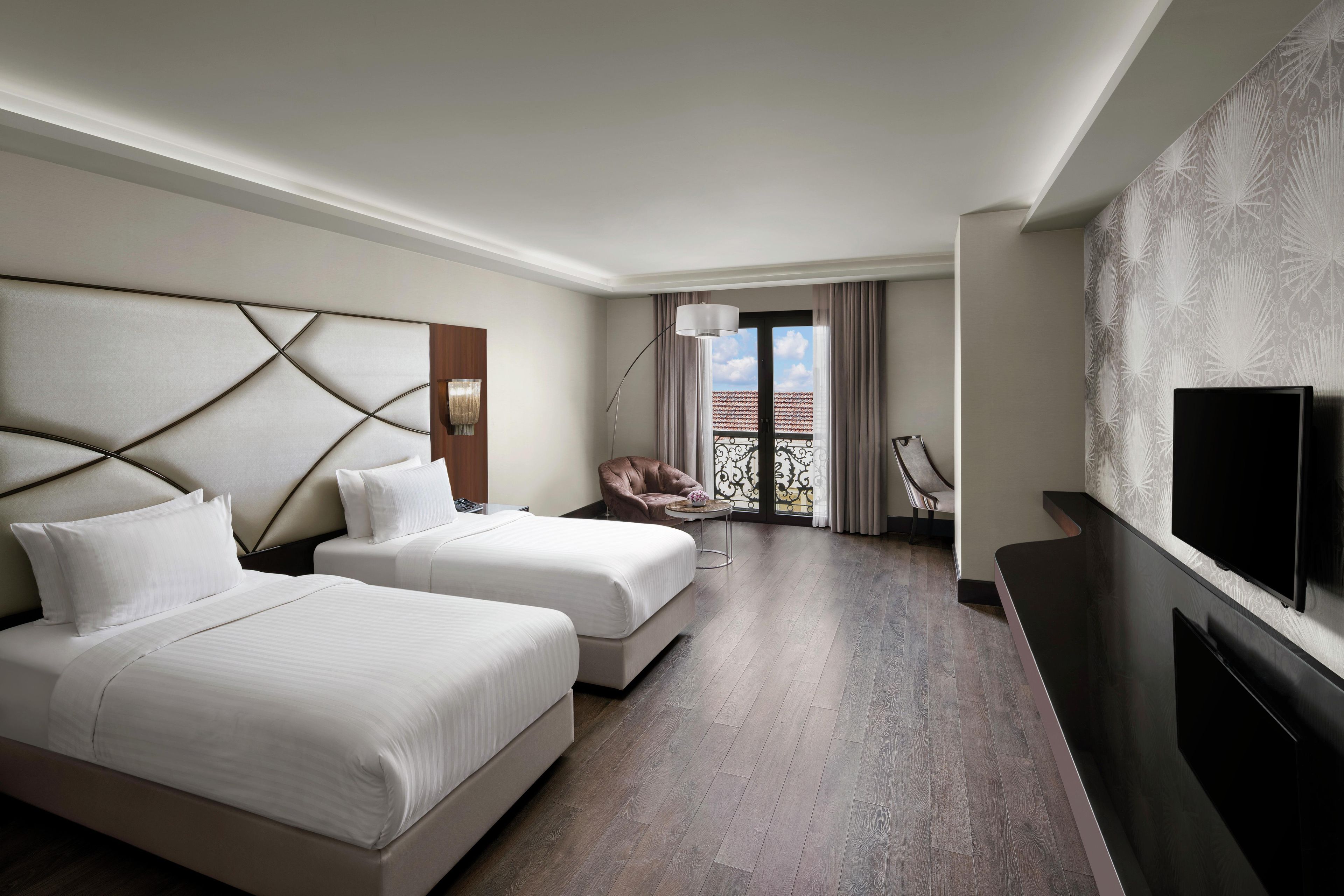 A hotel room with two beds, a TV, a balcony with a view, and a modern design.