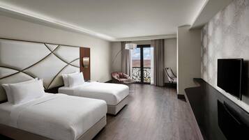 A hotel room with two beds, a TV, a balcony with a view, and a modern design.