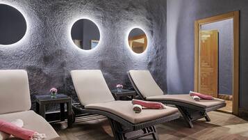 Un cuarto de spa con tres sillones reclinables, una mesita con un florero y una puerta de madera.