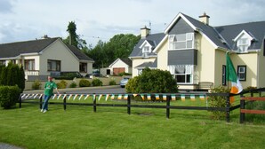 A residential area with houses, a grassy lawn, and a flag. - Ashfield Bed & Breakfast (Kenmare)
