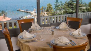 Une table à manger dressée pour quatre personnes, avec vue sur la mer et le port.