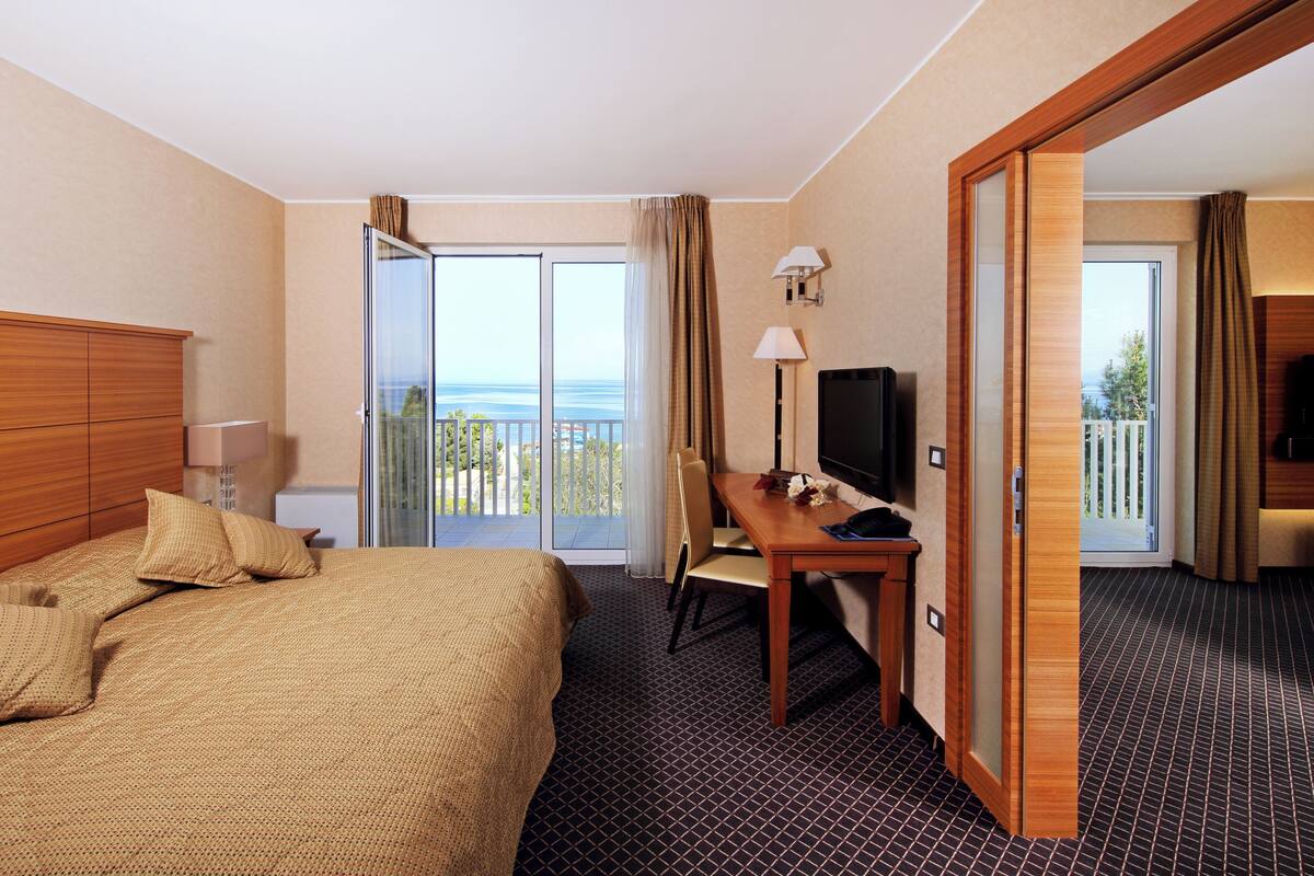 Une chambre d’hôtel comprenant un lit, un bureau avec une chaise, une télévision et une vue sur l’extérieur.