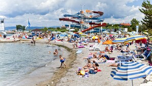 Une plage bondée, avec de nombreux parasols et beaucoup de monde.