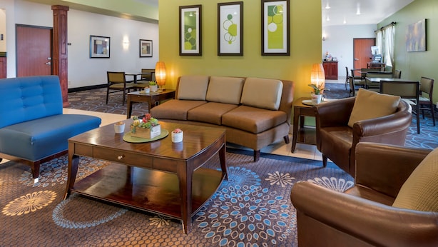 Un hall d’hôtel avec un canapé bleu, un canapé marron, une table basse en bois et un tapis à motifs.