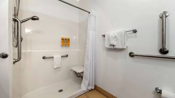 A bathroom with a walk-in shower, grab bars, a toilet with a raised seat, and a towel rack.