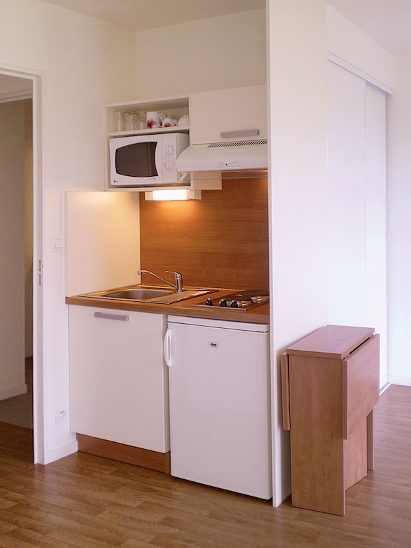A compact kitchenette with a microwave, stove, and sink.