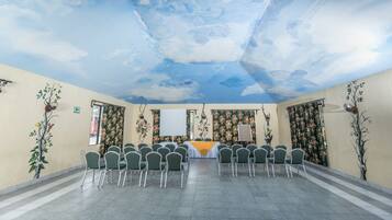 A conference room with a long table, chairs, floral wall decorations, and a ceiling mural.