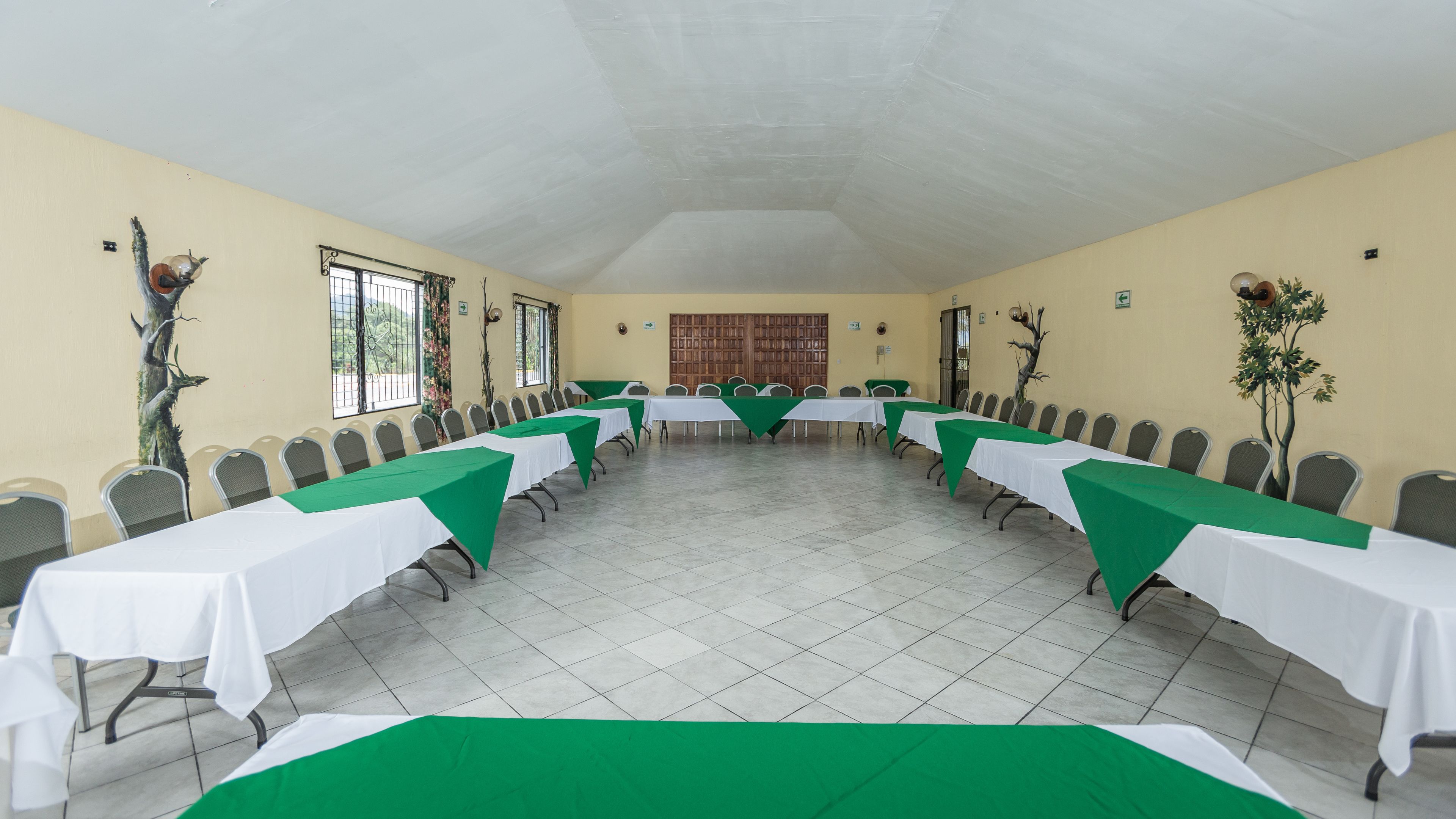 A conference room with long tables, chairs, and a tiled floor.