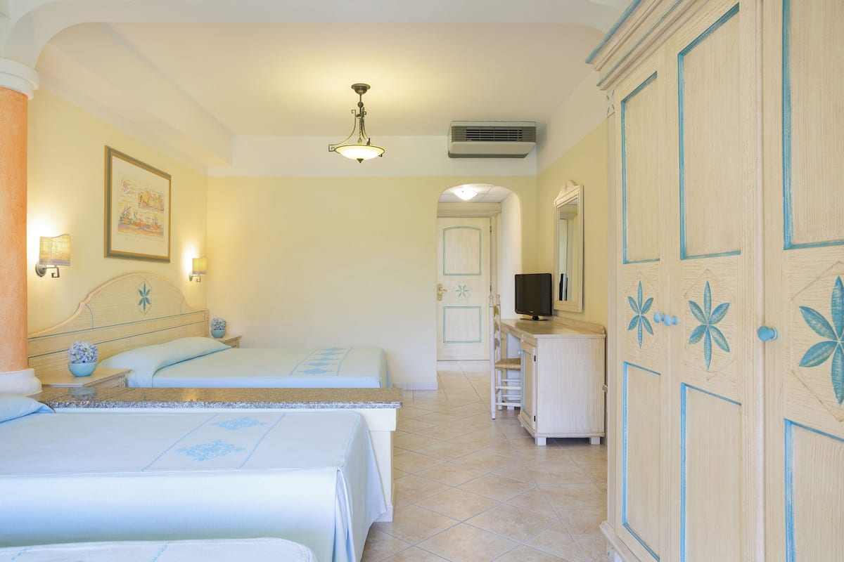 A hotel room with two beds, a television, and a cabinet.