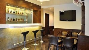 Een bar met een toonbank, verschillende krukken en een aan de muur bevestigde televisie.