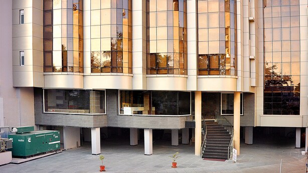 Een modern gebouw met een grote glazen gevel, een trap naar een inkom en een bord met de naam "Narayana" bovenaan.