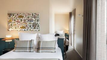 A hotel room with a bed, a nightstand, a lamp, a painting on the wall, and a window with curtains.