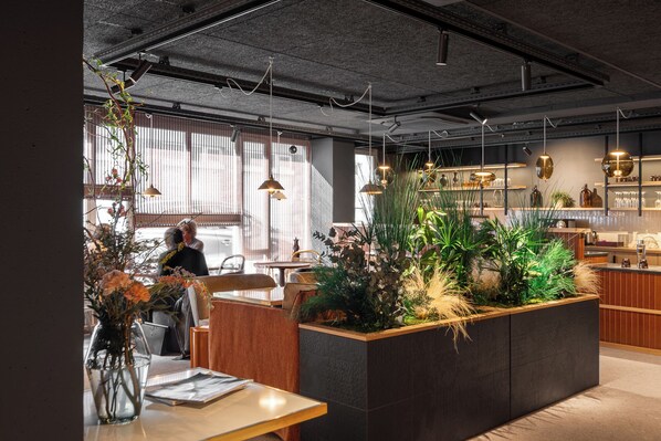 A modern interior with a central planter, wooden furniture, and pendant lighting. - Hôtel L'Adresse (Saint-Malo)
