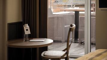 A hotel room with a round table, a chair, and a window with a view of the outside.