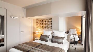 Una habitación de hotel con una cama grande, lámparas de noche, una obra de arte en la pared y una silla junto a la ventana.