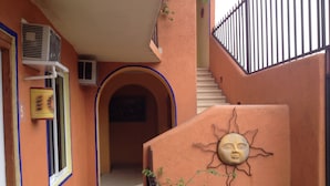 Una escalera conduce a un piso superior, con un adorno con forma de sol en la pared y una puerta con el símbolo de número.