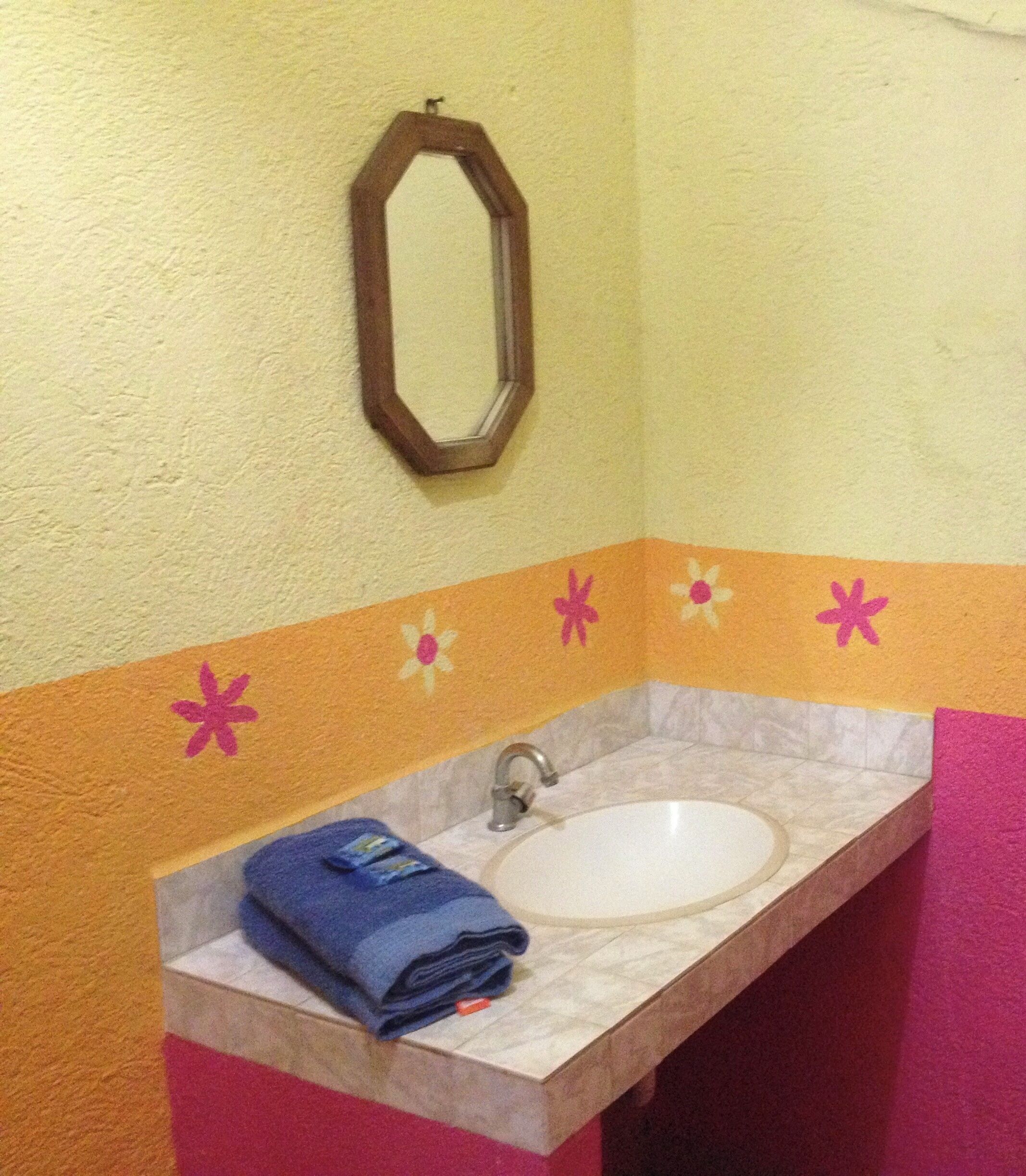 Un baño con lavamanos, espejo y un detalle decorativo en la pared.
