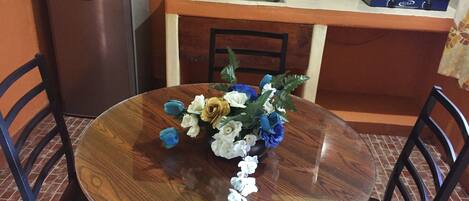 Una mesa de comedor con sillas, un florero, un refrigerador, un fregadero y una estufa.