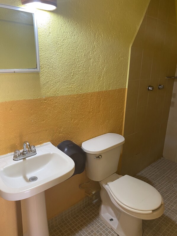 Un baño con lavamanos, inodoro y zona de ducha.