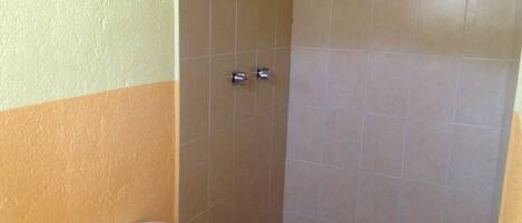 A bathroom with a toilet, a shower stall, and tiled walls.