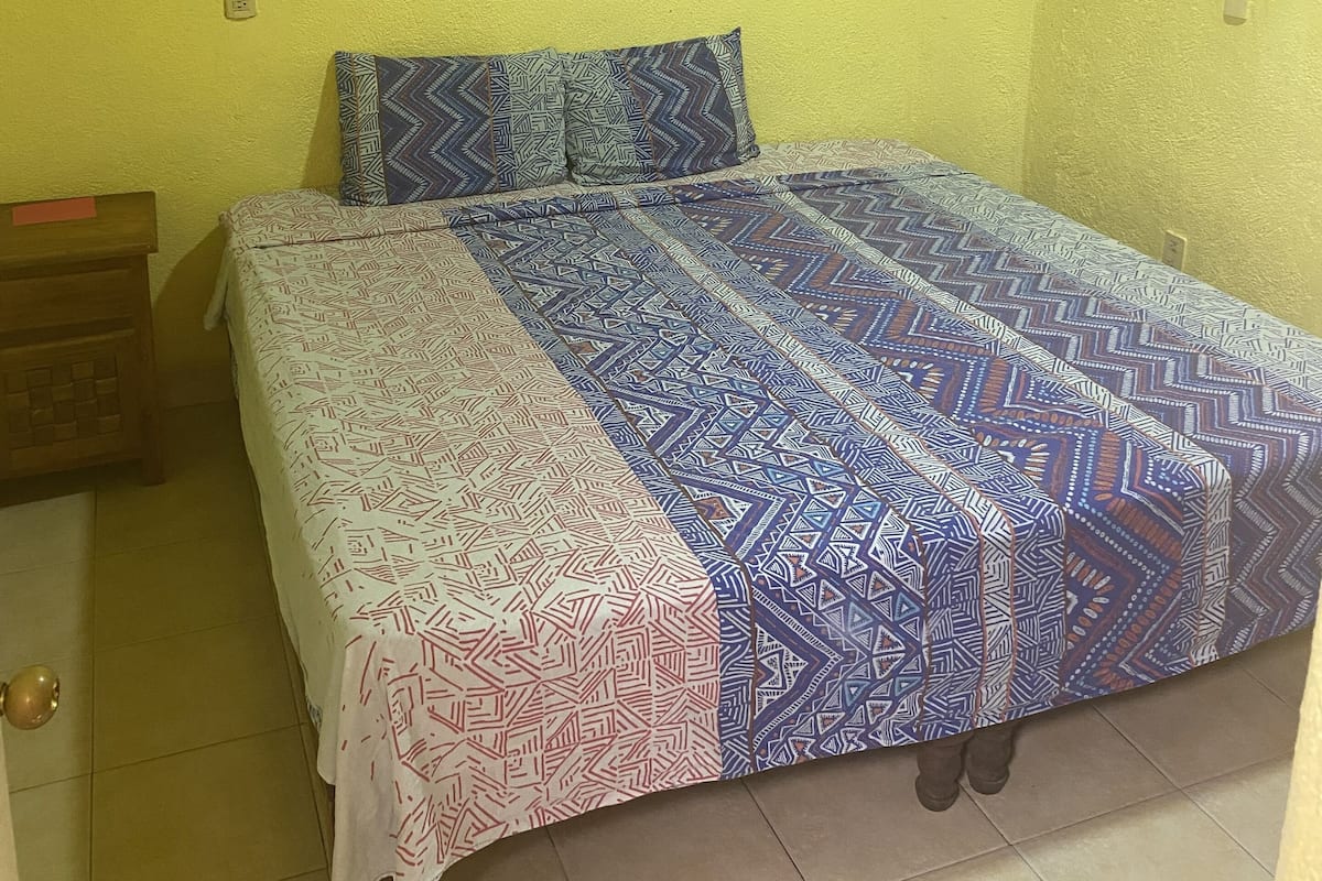 A bedroom with a bed, a nightstand, and two wall-mounted pictures.