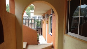 Una escalera que lleva a una puerta con ventana, rodeada por un muro color beige y una cerca de metal negro.