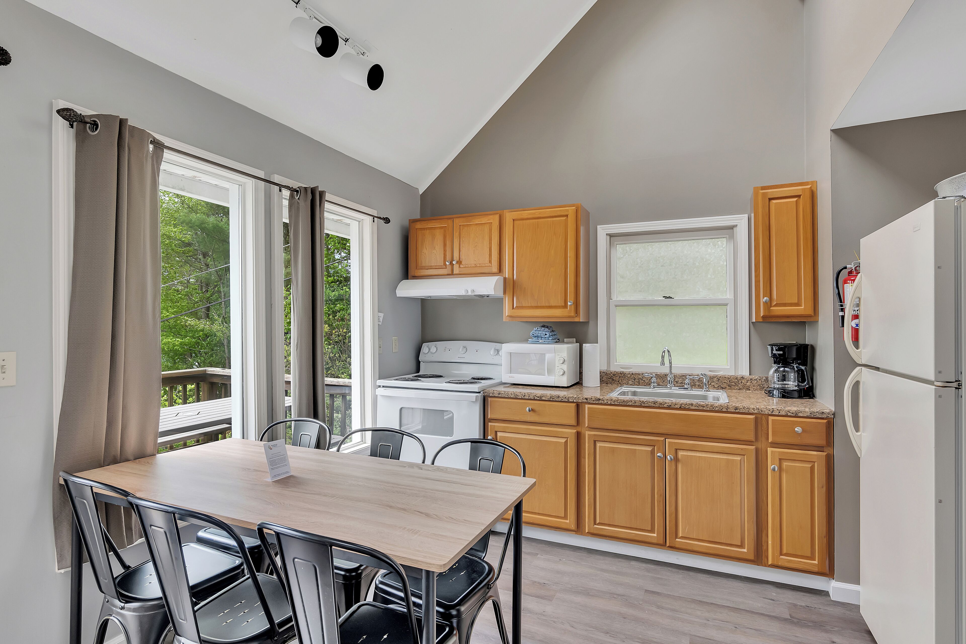 A modern kitchen with wooden cabinets, a white stove, a microwave, and a refrigerator.