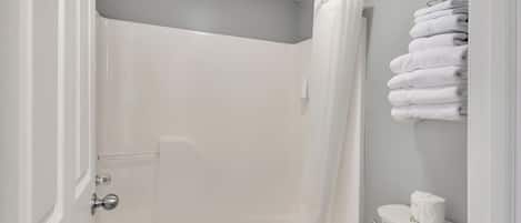 Un baño con ducha, inodoro y perchero para toallas.