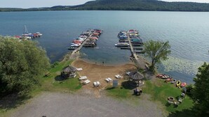 Un puerto deportivo con barcos amarrados, un pequeño pabellón y una zona ajardinada con sillas de descanso.