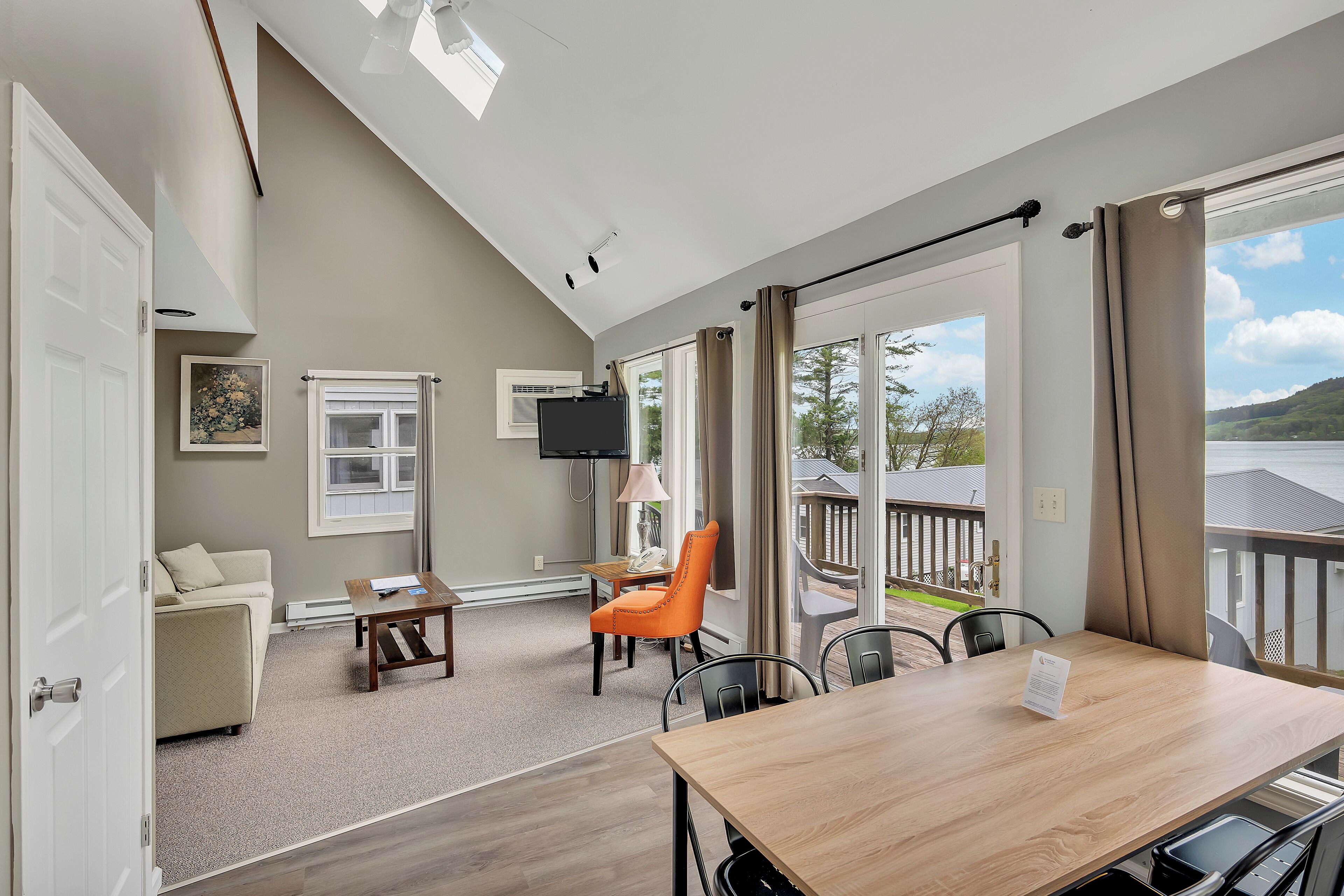A spacious room with a large window, a wooden table, and a comfortable seating area.