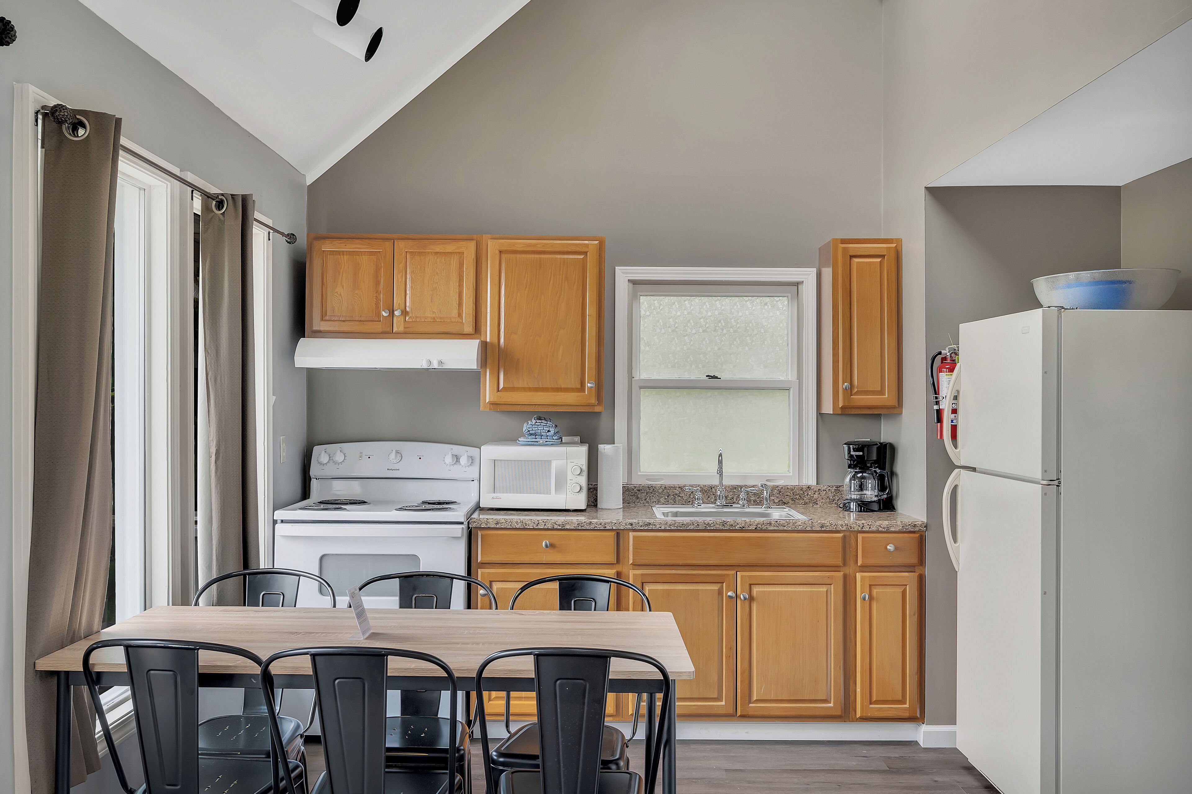 A compact kitchen with wooden cabinets, a white stove, a microwave, and a refrigerator.