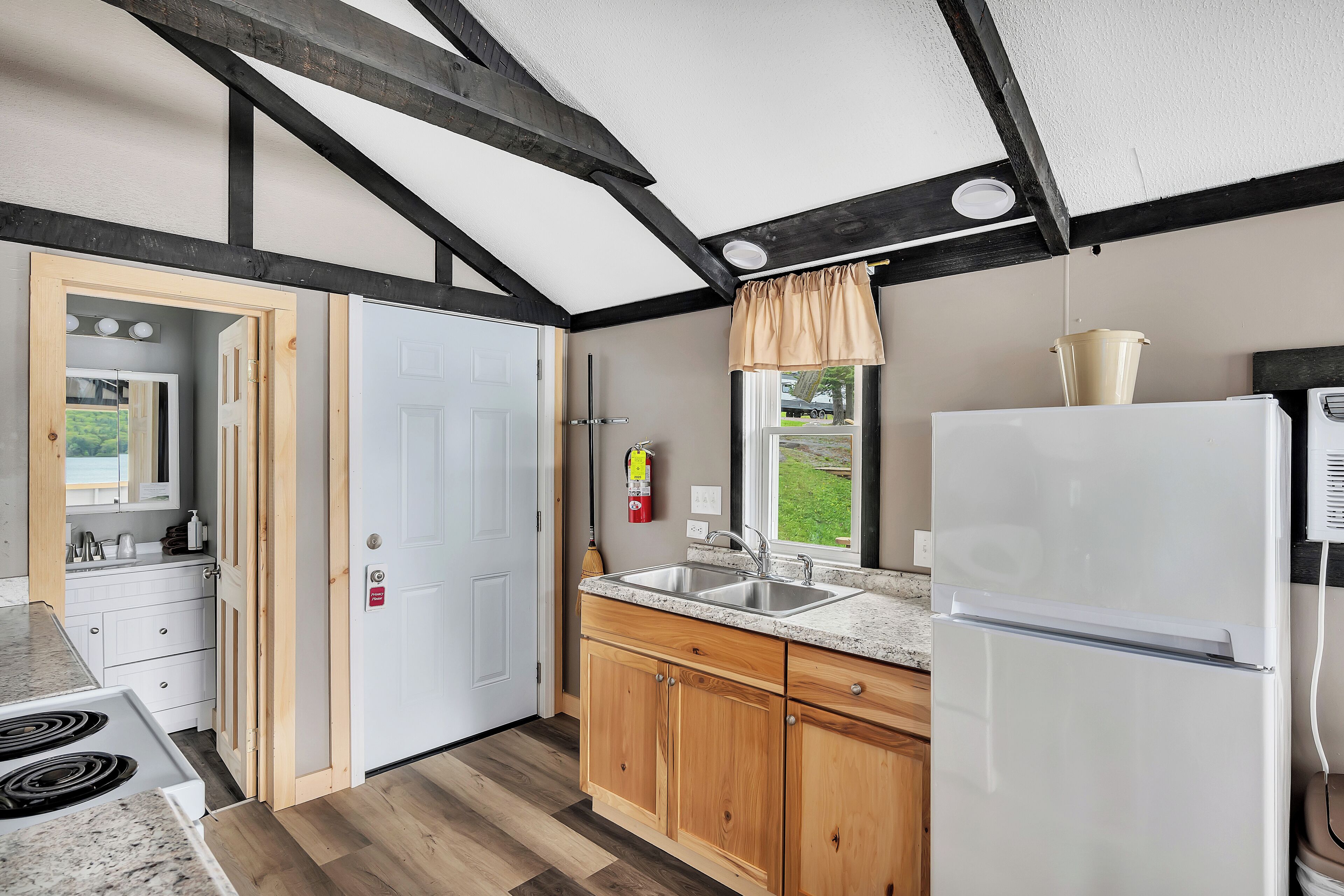 A kitchen with wooden cabinets, a white refrigerator, a sink, and a window with a view of the outdoors.