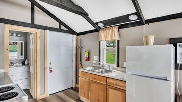 A kitchen with wooden cabinets, a white refrigerator, a sink, and a window with a view of the outdoors.