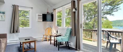 Una habitación acogedora con sofá, una mesita, una silla y un televisor montado en la pared.