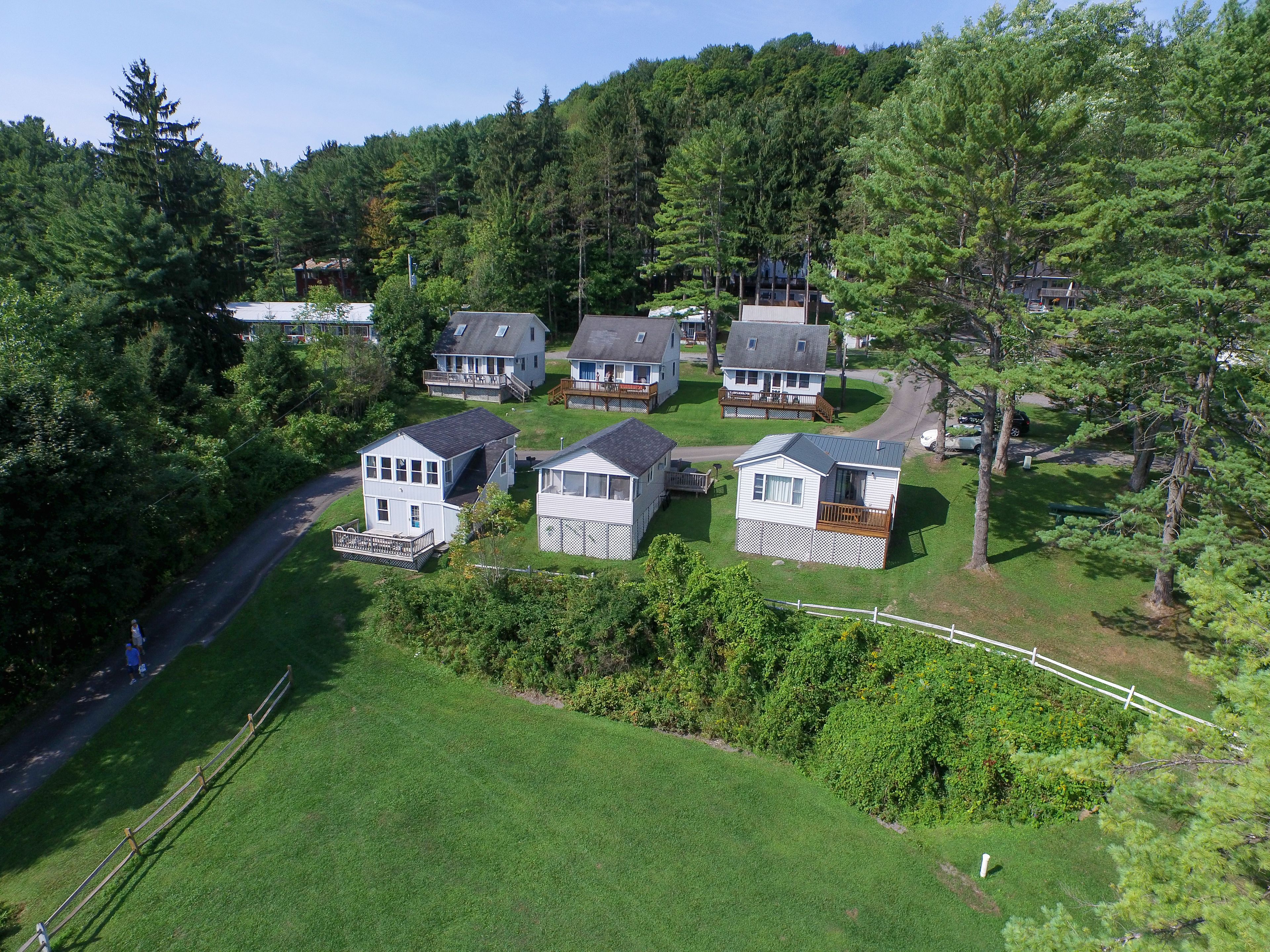 A cluster of small, single-story cabins with attached porches, surrounded by dense forest.