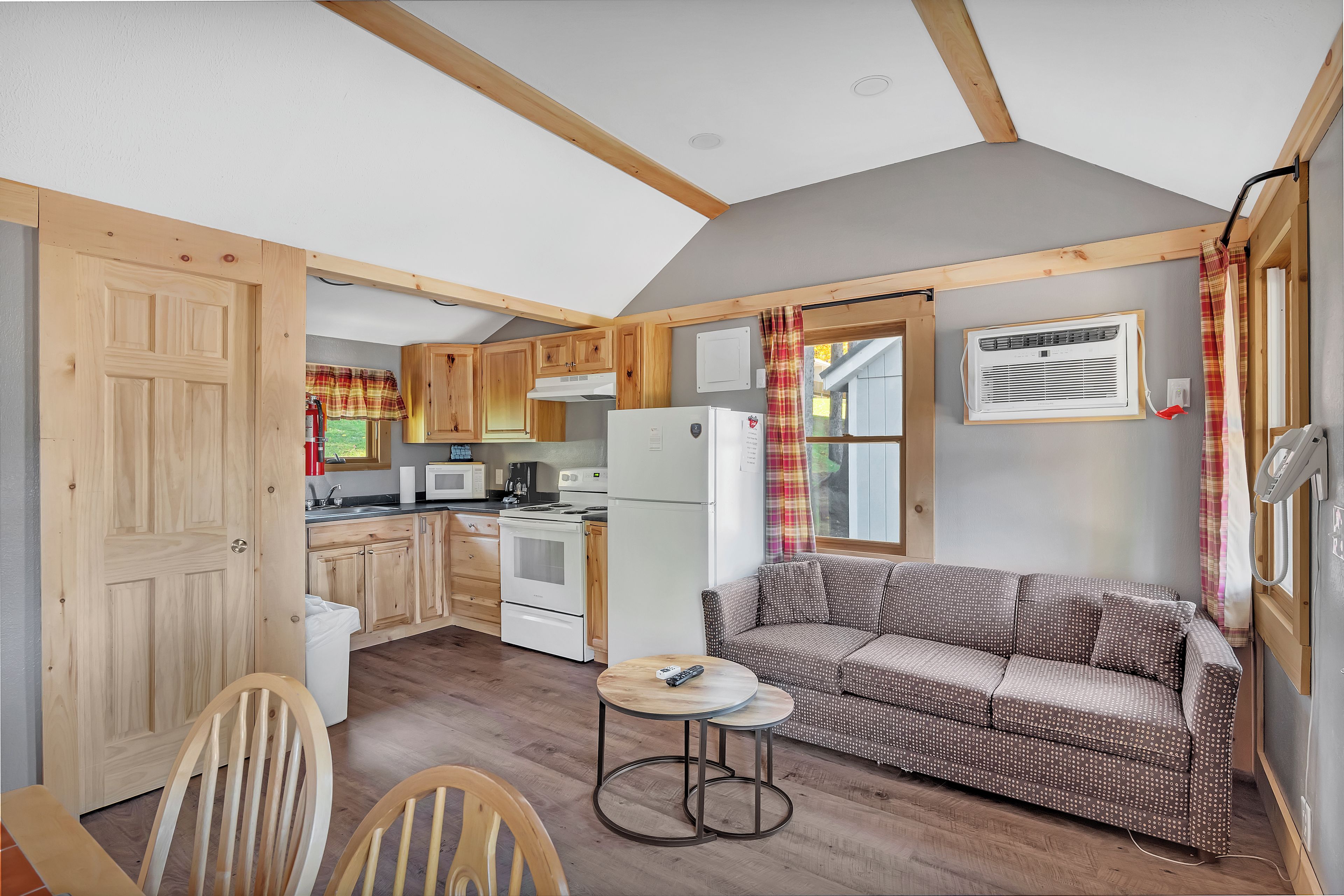A compact kitchen with wooden cabinets, a dining area with a round table and chairs, and a sofa.