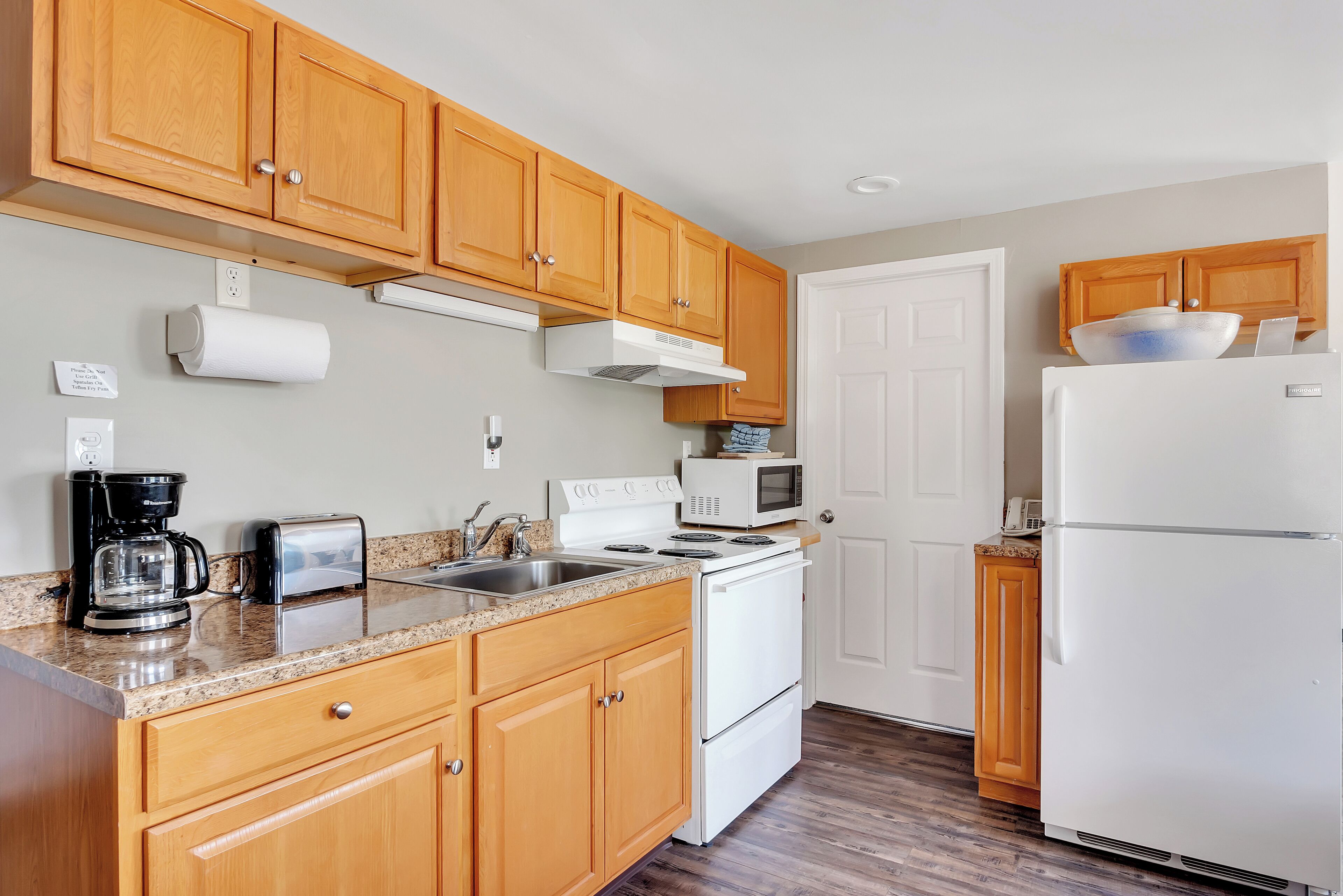 A kitchen with wooden cabinets, a white stove, a microwave, and a refrigerator.
