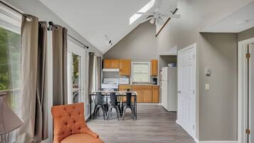 A modern kitchen with wooden cabinets, a dining area with a table and chairs, and a ceiling fan.