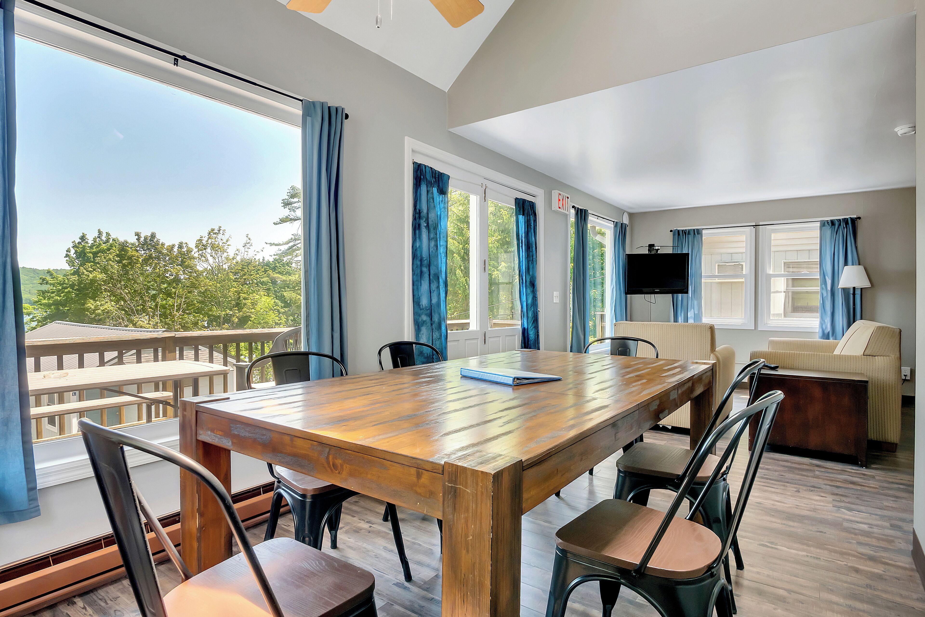 A spacious room with a large wooden table, several chairs, a sofa, and a TV.